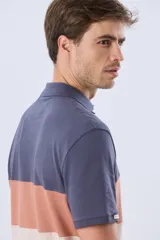 Remera polo de manga corta con diseño en bloques de color en tonos azul marino, blanco y verde militar, con bordado frontal y cierre de botones.