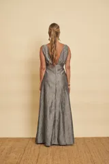 Vestido largo gris metalizado, con escote en V profundo, sin mangas y corte en la cintura con falda amplia.