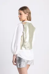 Chaleco sastrero dorado champagne de cuero, con botones metálicos.