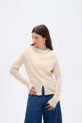 Saco de punto color crema, con cuello a la base, cierre frontal con botones y diseño holgado de manga larga.