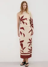Vestido midi entallado de diseño asimétrico con un solo hombro y manga larga, de color beige con estampado borgoña de hojas y detalles fruncidos en el cuerpo.