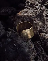 Brazalete rígido de diseño artesanal con textura irregular y acabado metálico, elaborado en bronce macizo.