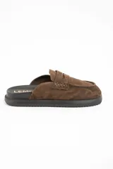 Zueco tipo mocasín destalonado confeccionado en gamuza color marrón, con suela de goma negra y plantilla anatómica.