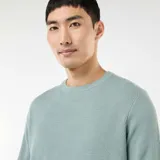 Sweater de punto con textura fantasía, cuello redondo y mangas largas con puños acanalados.