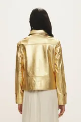 Campera de cuero negro al cuerpo, con cuello camisero, bolsillos de parche con solapa en el pecho y cierre frontal con broches a presión.