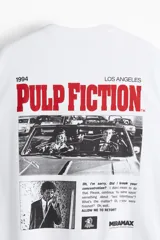 Remera de algodón de corte holgado con cuello redondo y mangas cortas con hombros caídos. Presenta un estampado pequeño en el pecho con el logo de la película Pulp Fiction.