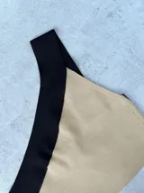 Top corto de tejido de punto, con diseño asimétrico de un solo hombro. La parte principal es de color lila y el tirante es de color naranja.