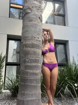 Top de bikini fucsia con un solo hombro y aro dorado en el centro.