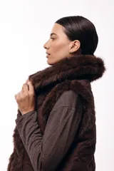 Chaleco acolchado color marrón con terminaciones de piel sintética en los bordes y cuello, aportando volumen y textura.