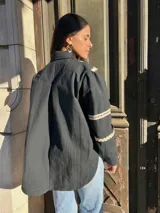 Camisa blanca de mangas largas con detalles de puntilla beige en cuello y puños, y cierre frontal con botones.