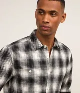 Camisa de franela a cuadros en blanco y negro, de corte comfort, con cuello inglés, abotonadura frontal, manga larga, bolsillo en el pecho y puños abotonados.