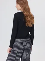Remera de manga larga y corte clásico con cuello redondo, de color negro con costuras en hilo rojo a contraste y logo bordado en el centro del pecho.
