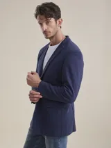 Blazer formal color negro, confeccionado en tela texturada, con solapas clásicas, cierre de dos botones frontales y bolsillos con solapa.