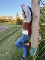 Chaleco tejido en mohair con diseño de guarda geométrica en la parte superior. Presenta una combinación de colores gris, blanco y beige, con cuello redondo y corte recto.