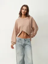 Buzo corto color beige con cuello redondo y mangas largas.