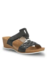 Sandalias Hush Puppies modelo Bax III de color negro con plataforma corrida de estilo amaderado. Presenta una faja delantera con diseño cruzado en rombos decorados con pequeños tachas metálicas, unidas mediante una argolla plateada a las tiras superiores con cierre de velcro ajustable.