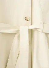 Chaqueta de algodón elastizado color beige, con cuello alto, cierre frontal de botonadura simple, mangas largas y cinturón ajustable del mismo tejido.