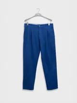 Pantalón de vestir color crema, confeccionado en tejido ligero de algodón con textura seersucker. Tiene corte recto, bolsillos laterales y traseros, cierre con botón y cremallera, y parche con logo de la marca.