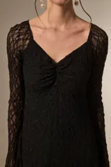 Vestido corto de encaje color crema, con mangas largas, cuello en V y falda evasé con terminación de volado.