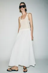 Falda midi de corte en A, color blanco, confeccionada en algodón con cintura elástica de tiro alto y forro interior a tono.