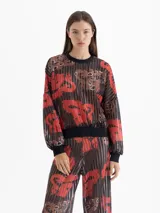 Buzo de punto calado con estampado full print en tonos rojos, marrones y negros. Presenta mangas amplias y terminaciones en cuello, puños y cintura en tela negra que genera contraste.