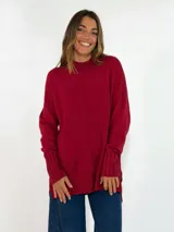 Sweater de punto color bordó, con cuello alto, mangas largas y puños acanalados con diseño de trenzas. Presenta un corte holgado con aberturas laterales en el ruedo.