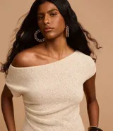 Blusa de punto color crema, con escote asimétrico, mangas cortas, textura y fruncido lateral.