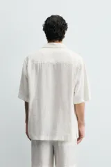Camisa negra de manga corta, confeccionada en lino con corte relaxed fit, cuello bowling y cierre frontal de botonadura.