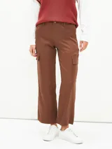 Pantalón cargo de corte recto y tiro medio, color marrón, con bolsillos laterales con solapa y cierre frontal con botón y cremallera.