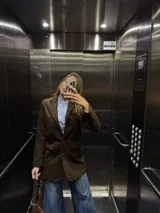 Tapado de lana color marrón, de corte recto y diseño minimalista. Presenta solapas clásicas, cierre frontal con botones y bolsillos laterales con tapa.