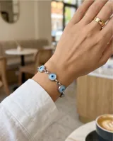 Pulsera de eslabones de acero con dijes circulares tipo ojo turco en tonos celestes y blancos.