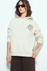 Buzo canguro color marrón con capucha y estampado de un corazón anatómico en azul en el pecho. De silueta relajada y calce cómodo.