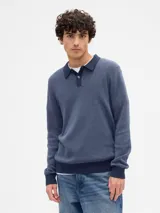 Buzo de punto tipo polo con cuello camisero y cierre frontal de botones. Presenta puños y ruedo acanalados en un tono azul más oscuro que el cuerpo de la prenda.