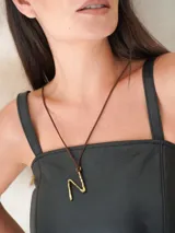 Collar con dije de letra "P" en bronce y cordón de cuero marrón.