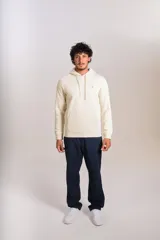 Hoodie de color beige con capucha, cordones ajustables y bolsillo tipo canguro frontal. Presenta el logo de la marca bordado en el pecho.