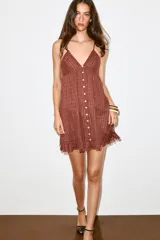 Vestido mini marrón terracota con finas rayas verticales de hilo metalizado, escote en V, tirantes finos ajustables, cierre frontal con botones y detalle de volados desflecados en el borde inferior.