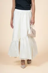 Falda larga color crudo, de silueta amplia con volado en el ruedo y cintura elástica.