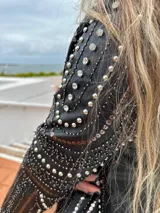 Chaqueta negra de cuero sintético con tachas plateadas, lentejuelas y strass.