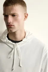 Hoodie ligero de corte regular fit color blanco, confeccionado en algodón, con capucha ajustable mediante cordón, mangas largas y bolsillo frontal tipo canguro.