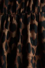 Vestido midi con estampado de leopardo, cuello camisero, botones frontales y mangas cortas con detalle de lazos. Cuenta con una costura fruncida con cinturón para atar en la cintura y falda con leve vuelo.