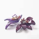 Caravanas con diseño floral en tonos violeta y morado, elaboradas en resina con acabado brillante y centro decorativo metálico.