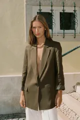 Blazer de lino color verde militar, con cuello solapa, hombreras y manga larga con puño revuelto con detalle a rayas. Cuenta con cierre frontal de un botón y bolsillos delanteros con solapa.