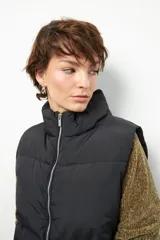 Chaleco puffer negro sin mangas, corto a la cintura y con cordones ajustables.