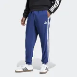 Pantalón Adidas Essentials 3 Rayas de corte clásico, color azul, con cintura elástica con cordón ajustable, bolsillos frontales y puños elásticos. Presenta las emblemáticas tres tiras blancas a los lados de las piernas y el logo de la marca bordado en blanco.