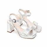 Sandalia de cuero plateado metalizado, con taco alto ancho, plataforma delantera, tira frontal y pulsera ajustable al tobillo con hebilla.