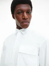 Camisa blanca de manga larga con cuello clásico y un bolsillo de parche en el pecho.