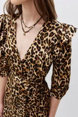 Vestido midi con estampado animal print de leopardo, escote en V cruzado, mangas 3/4 y detalles de volados en el escote, hombros y ruedo.