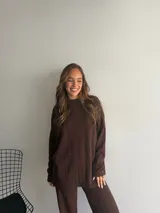 Buzo de punto color marrón chocolate, con cuello redondo y diseño holgado de manga larga con textura de trenzas verticales.