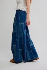 Pantalón flare de tiro alto, color azul, con diseño de patchwork y costuras visibles en contraste. Presenta perneras anchas de corte fluido.