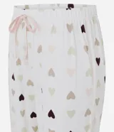 Pantalón de pijama estilo jogger con estampa de corazones en tonos suaves. Presenta cintura elástica con cordón ajustable y detalle de friso lateral, confeccionado en tejido peach touch de tacto suave.